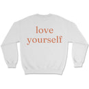 Neutral sweatshirt with small “be kind” text on front chest and bold “love yourself” text across back