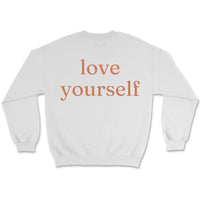 Neutral sweatshirt with small “be kind” text on front chest and bold “love yourself” text across back